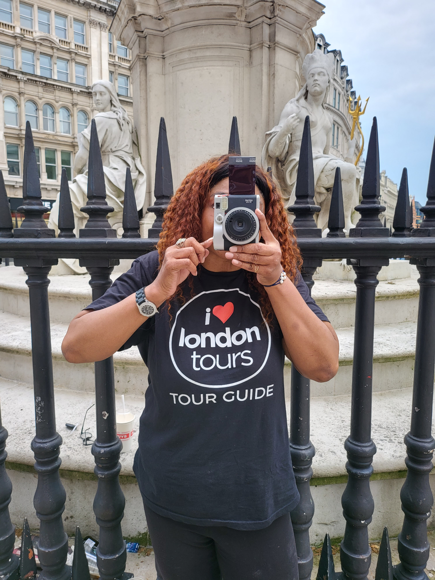 Professional tour guide with camera photographing London monument during guided walking tour